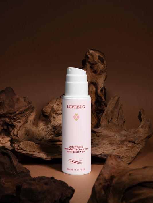 LOVEBUG Brightening Face and Body Exfoliator on driftwood against a warm brown backdrop